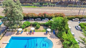 A swimming pool with a geometric tile design, surrounded by a paved area with lounge chairs and umbrellas. - Homiday - Residence Prestige, Interno 10 (Pineto)
