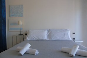 A hotel room with a bed, white linens, a lamp, and artwork on the wall. - Homiday - Residence Prestige, Interno 10 (Pineto)