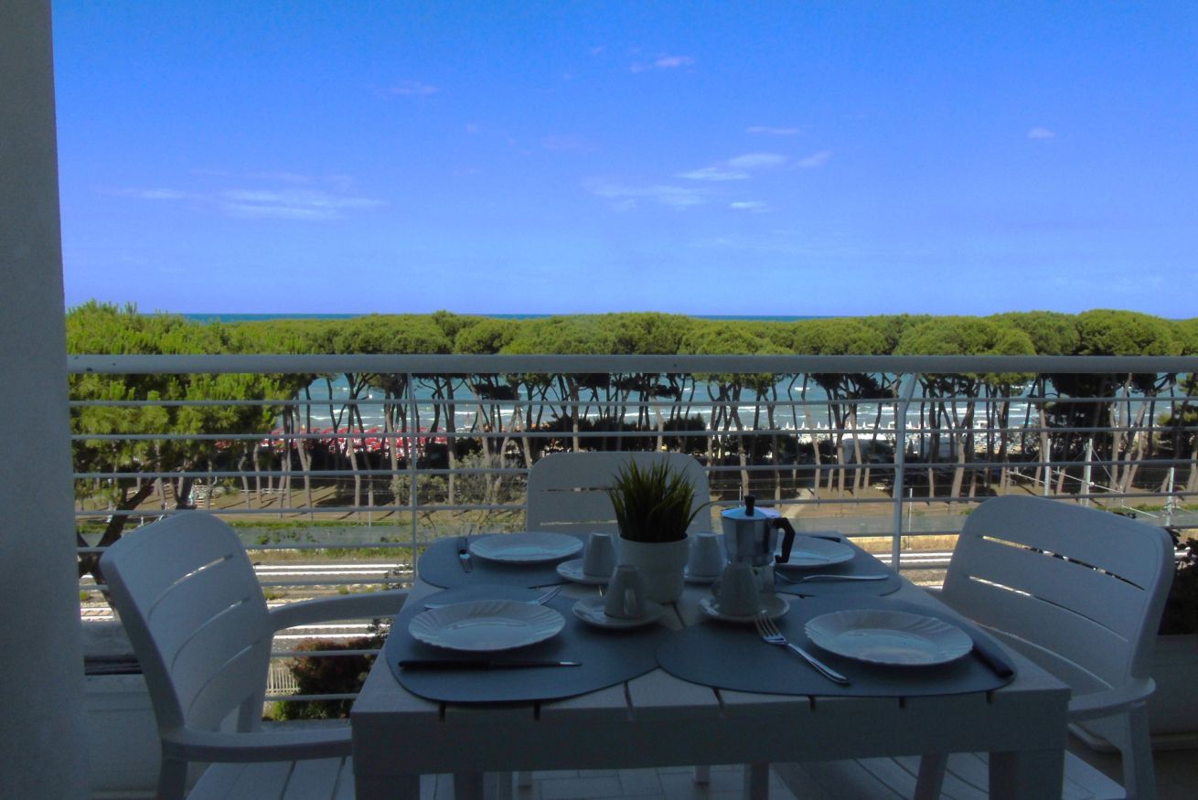 A table set for dining with a view of the sea and greenery.