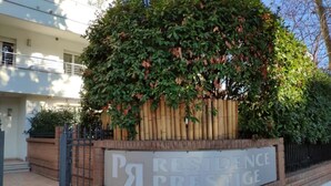 Indicador de 'Residence Prestige' amb un gran arbre i una paret de maó.