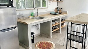 Una cuina moderna amb un frigorífic d'acer inoxidable, un forn integrat, un rentamiques i una finestra amb vista a vegetació.