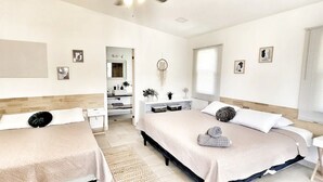 Habitació d'hotel amb dos llits, una taula, un mirall, una petita arca i una finestra.