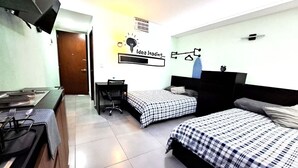 Une chambre d’hôtel avec deux lits, un bureau, une chaise et un téléviseur fixé au mur.