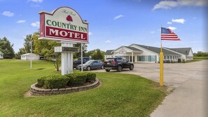 Cartel de Country Inn Motel, un estacionamiento y un edificio con una bandera estadounidense.