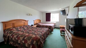 Habitación de hotel con dos camas, televisión, escritorio y ventana con cortinas.