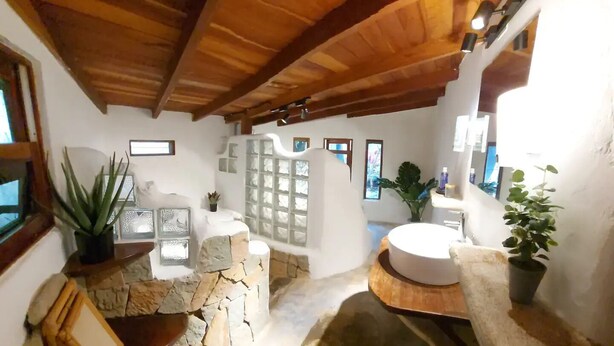 A rustic bathroom with stone walls, wooden beams, and a round sink. - sharonus cabin (Tamarindo)