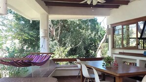 A covered outdoor area with a dining table, chairs, a hammock, and a ceiling fan. - sharonus cabin (Tamarindo)