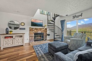 Una sala de estar moderna con chimenea, una escalera y vistas al exterior.