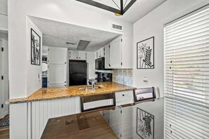 A modern kitchen with white cabinets, a granite countertop, and stainless steel appliances.
