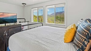 A bedroom with a bed, a television, and two windows with blinds. - Mountain View Condo w/ Indoor Pool & Hot Tub (Gatlinburg)