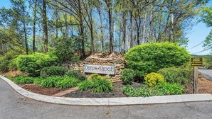 A sign for Deer Ridge Mountain Resort surrounded by lush greenery and a stone wall. - Mountain View Condo w/ Indoor Pool & Hot Tub (Gatlinburg)