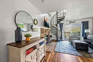 Una sala de estar con chimenea, una escalera en espiral y vistas al exterior.