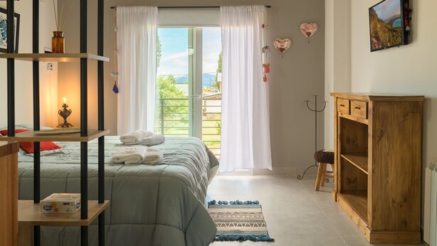 Un dormitorio con una cama, un armario de madera, un televisor y una ventana con cortinas.