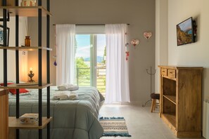 A bedroom with a bed, a wooden cabinet, a TV, and a window with curtains.