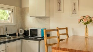 Una cocina con armarios blancos, microondas, tostadora y una mesa de comedor de madera.