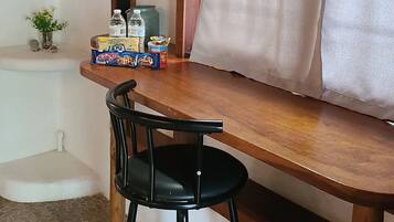 Una mesa de comedor de madera con una silla negra, una estantería con libros y un letrero que dice 'Dream Big', y una ventana con cortinas.
