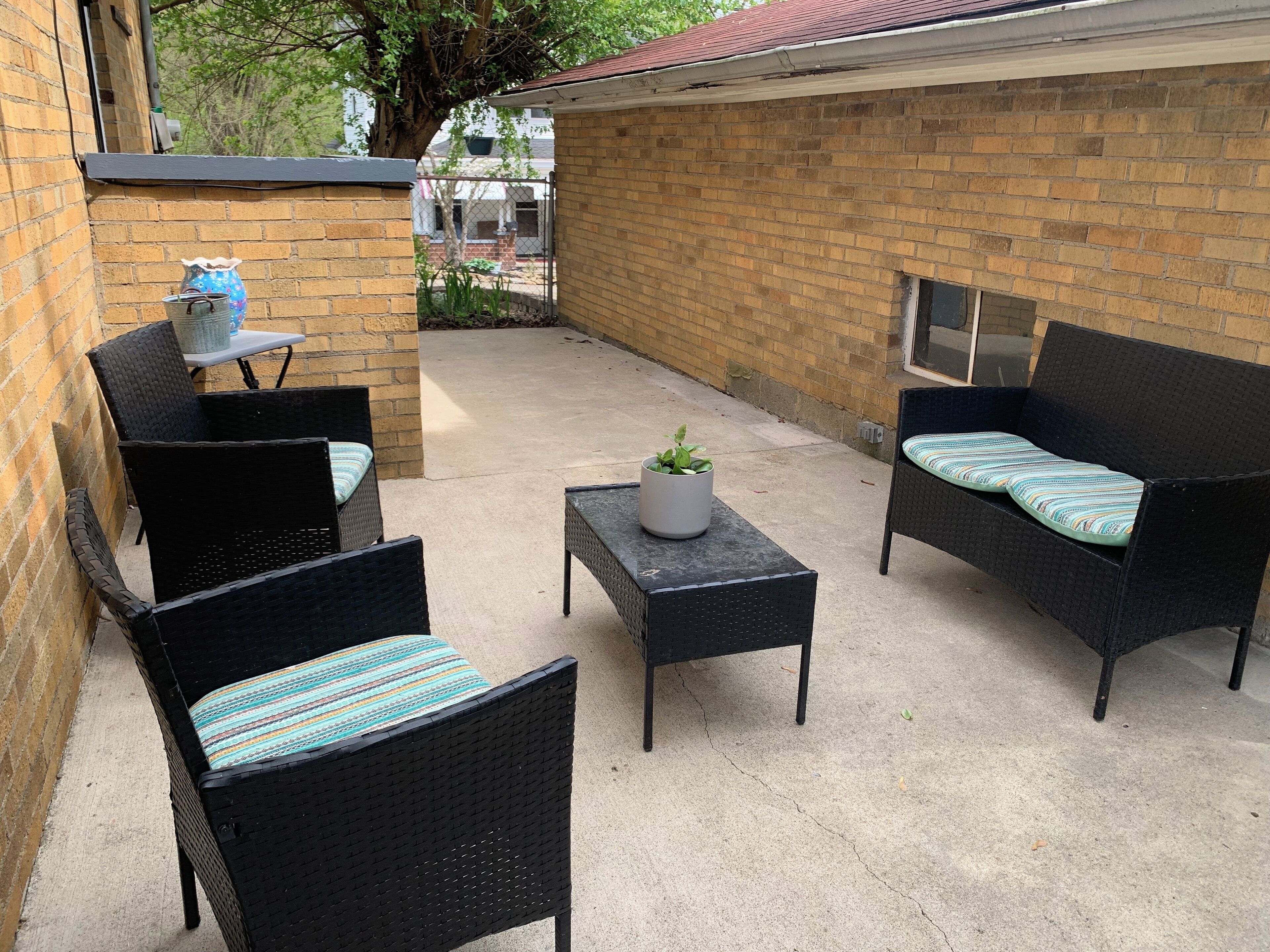 Une terrasse extérieure avec des meubles en osier, une petite table et une plante en pot.