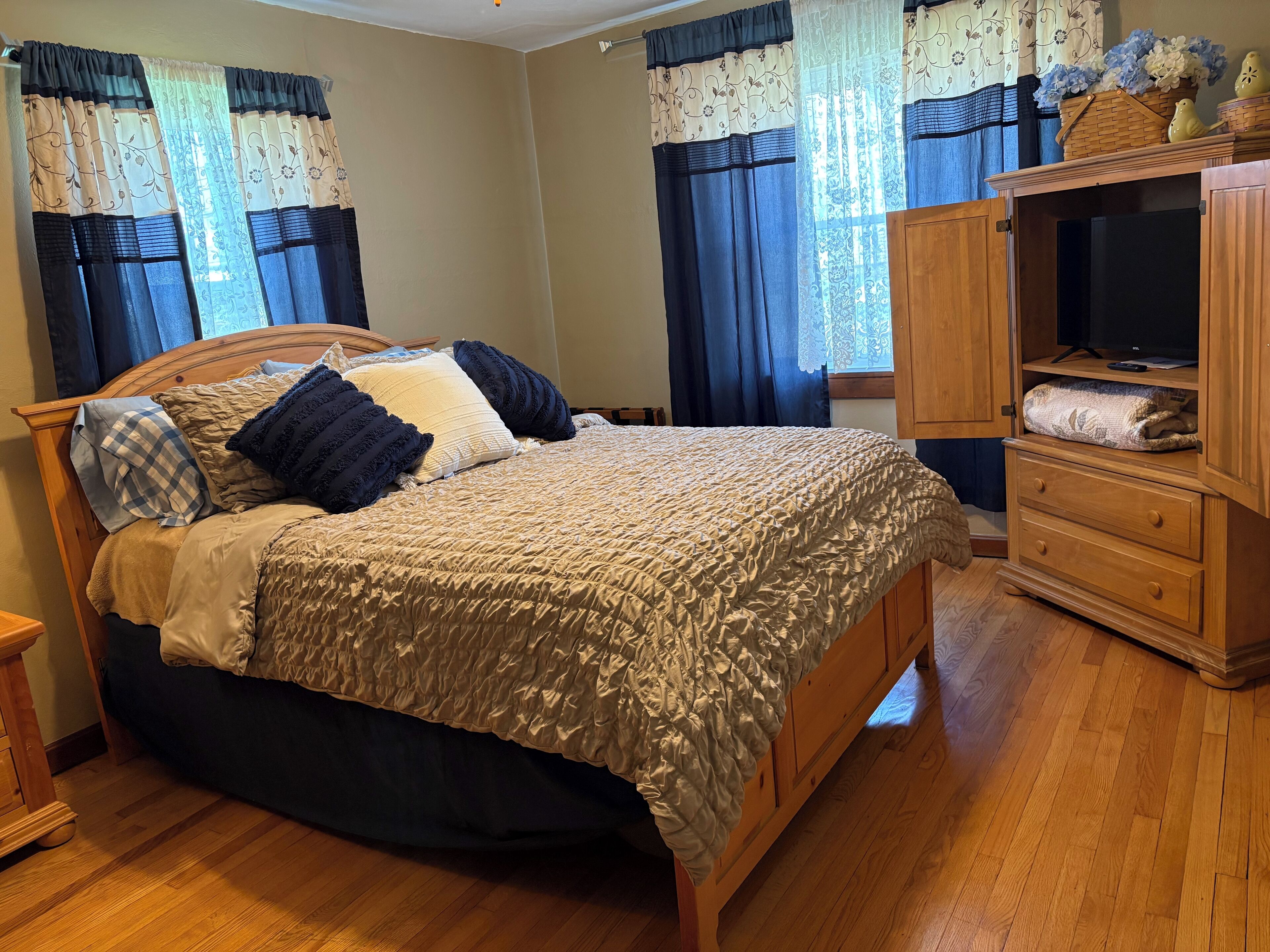 Ein Schlafzimmer mit einem hölzernen Bett, einer Holzkommode und einem Fernseher auf einem Holzkasten.