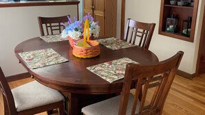 A dining area with a wooden table, six chairs, and a decorative centerpiece. - The Kitchie Kottage/ House (Portsmouth)