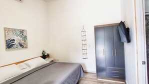 Een slaapkamer met een bed, een plafondventilator, een kledingkast en een deur.