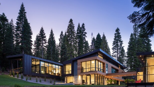 A modern two-story house with large windows and a covered outdoor area.