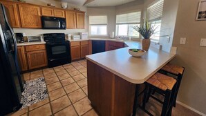 Una cocina con armarios de madera, microondas, estufa y una isla grande con taburetes de bar.