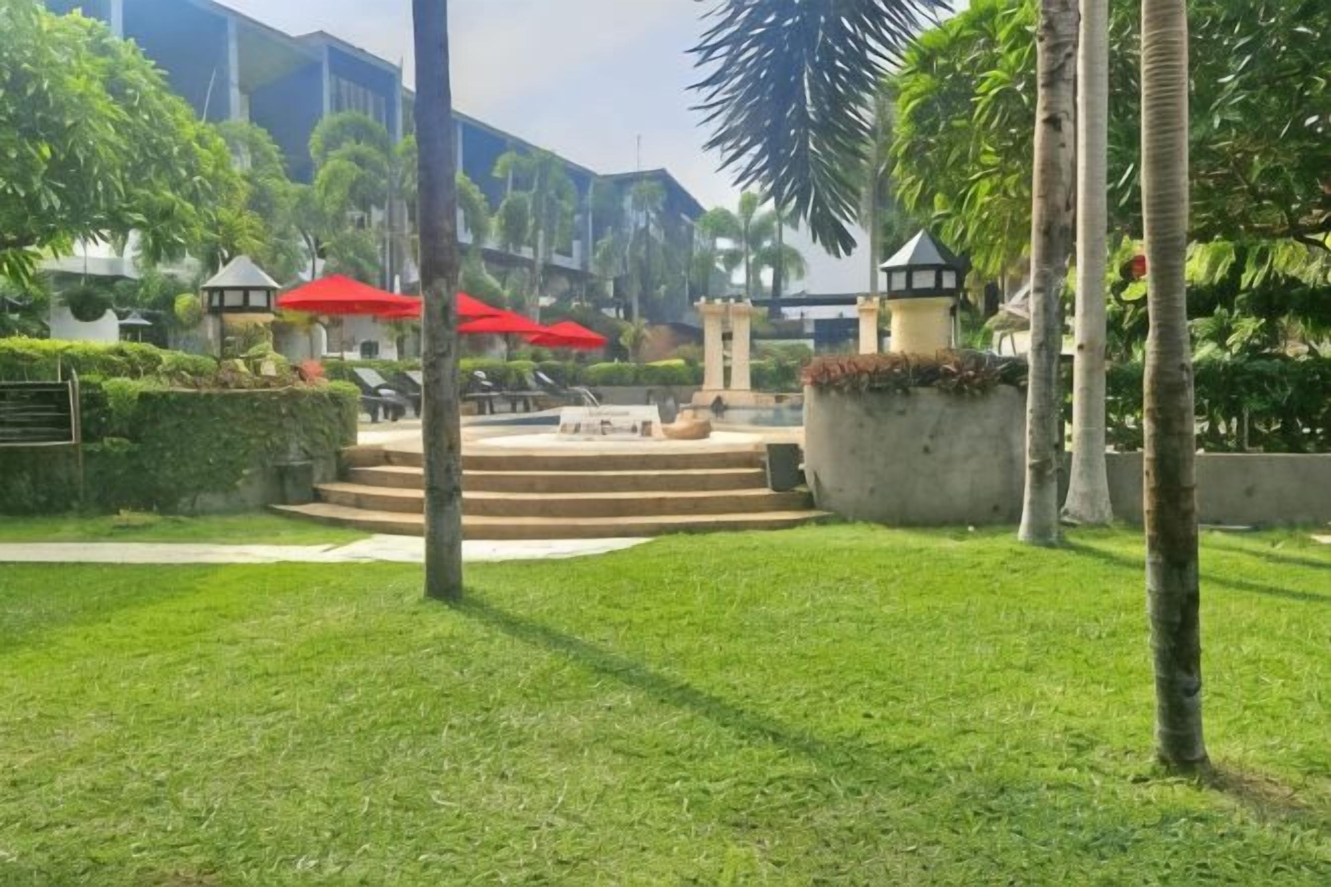 Un patio con piscina, sombrillas rojas y una escalera que lleva a un edificio.