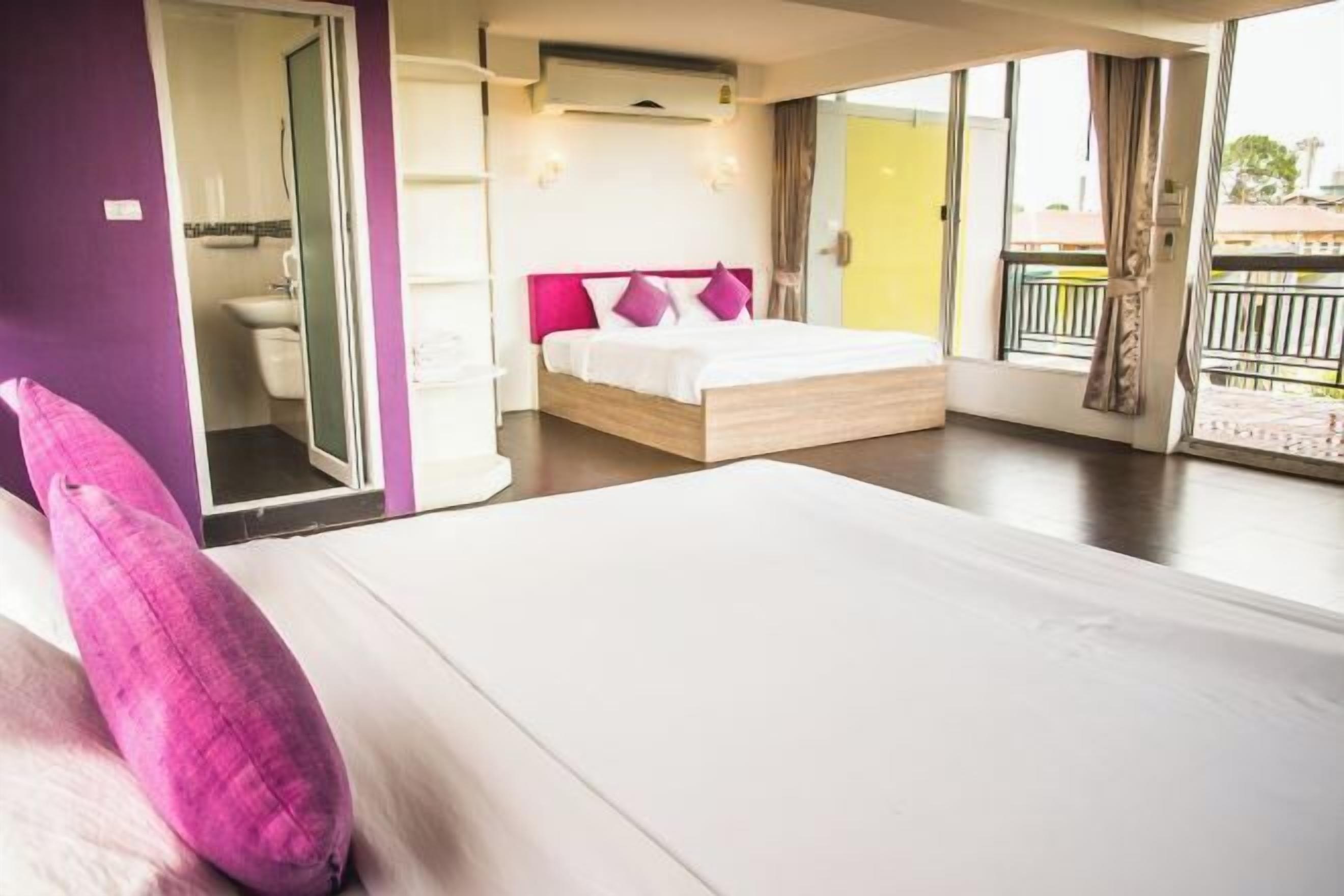A bedroom with a bed, a bathroom, and a balcony.