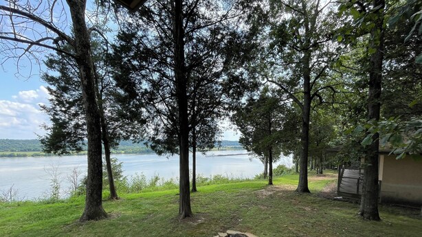 Een vakantiehuis aan het meer met vuurplaats, bomen en uitzicht op het water.