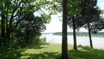 Een gazon met bomen en een meer in de achtergrond.