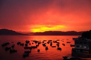 A sunset over a body of water with boats and buildings in the foreground. - Fuding Yushan Island Luzhu Village Jiayuan Homestay (Fuding)