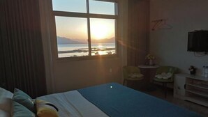 A hotel room with a bed, a chair, a small table, and a TV.