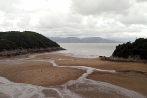 A beach with a sandy shore, a small water channel, and a forested hill in the background. - Fuding Yushan Island Luzhu Village Jiayuan Homestay (Fuding)