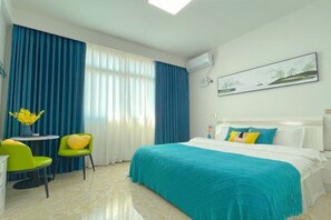 A hotel room with a bed, a desk, two chairs, a window with curtains, and a painting on the wall. - Fuding Yushan Island Luzhu Village Jiayuan Homestay (Fuding)