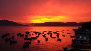 A sunset over a body of water with boats and a building in the foreground.