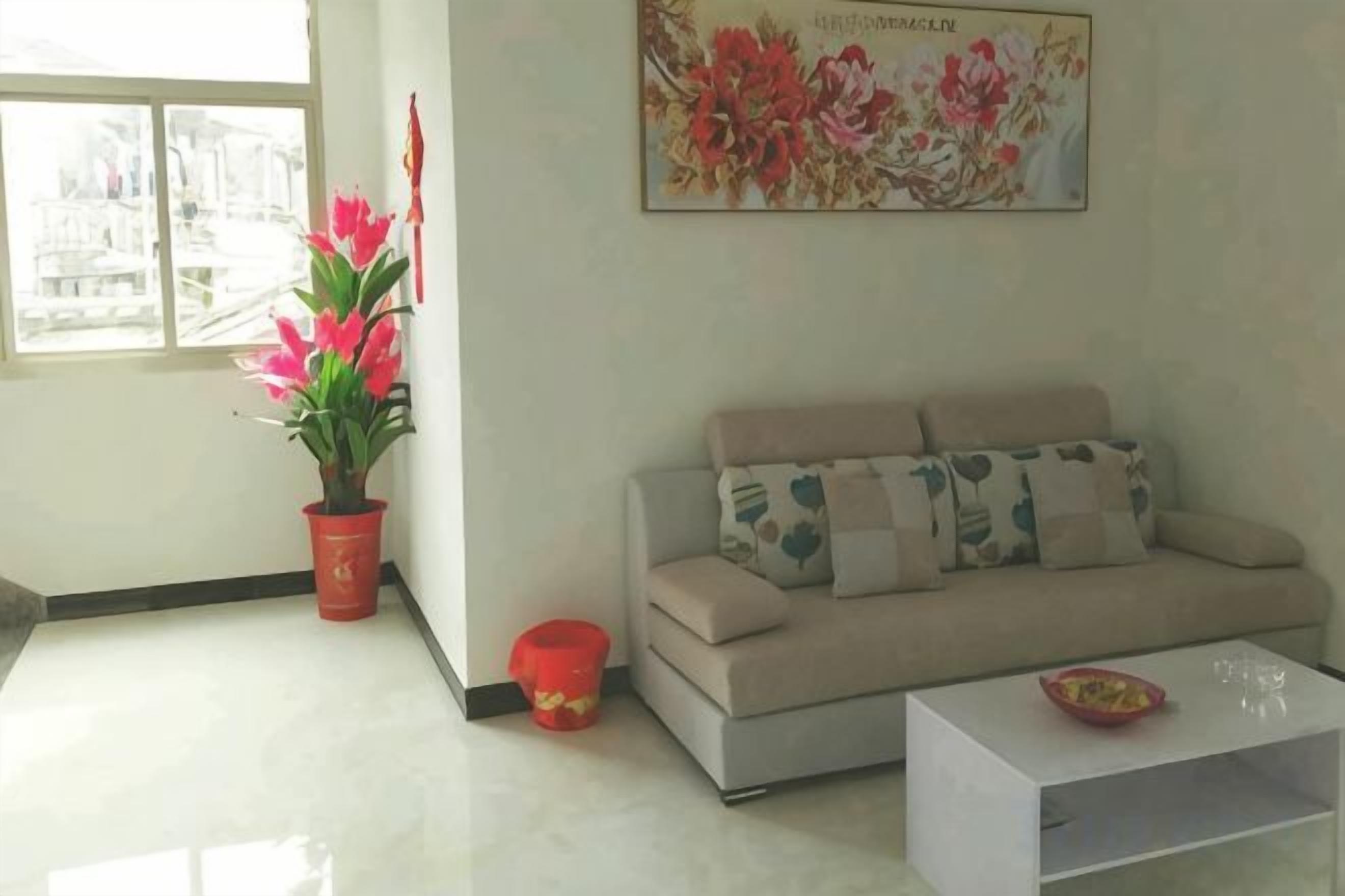 A living room with a sofa, a coffee table, a potted plant, and a window.