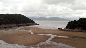 A beach with a sandy shore and a calm sea under a cloudy sky.