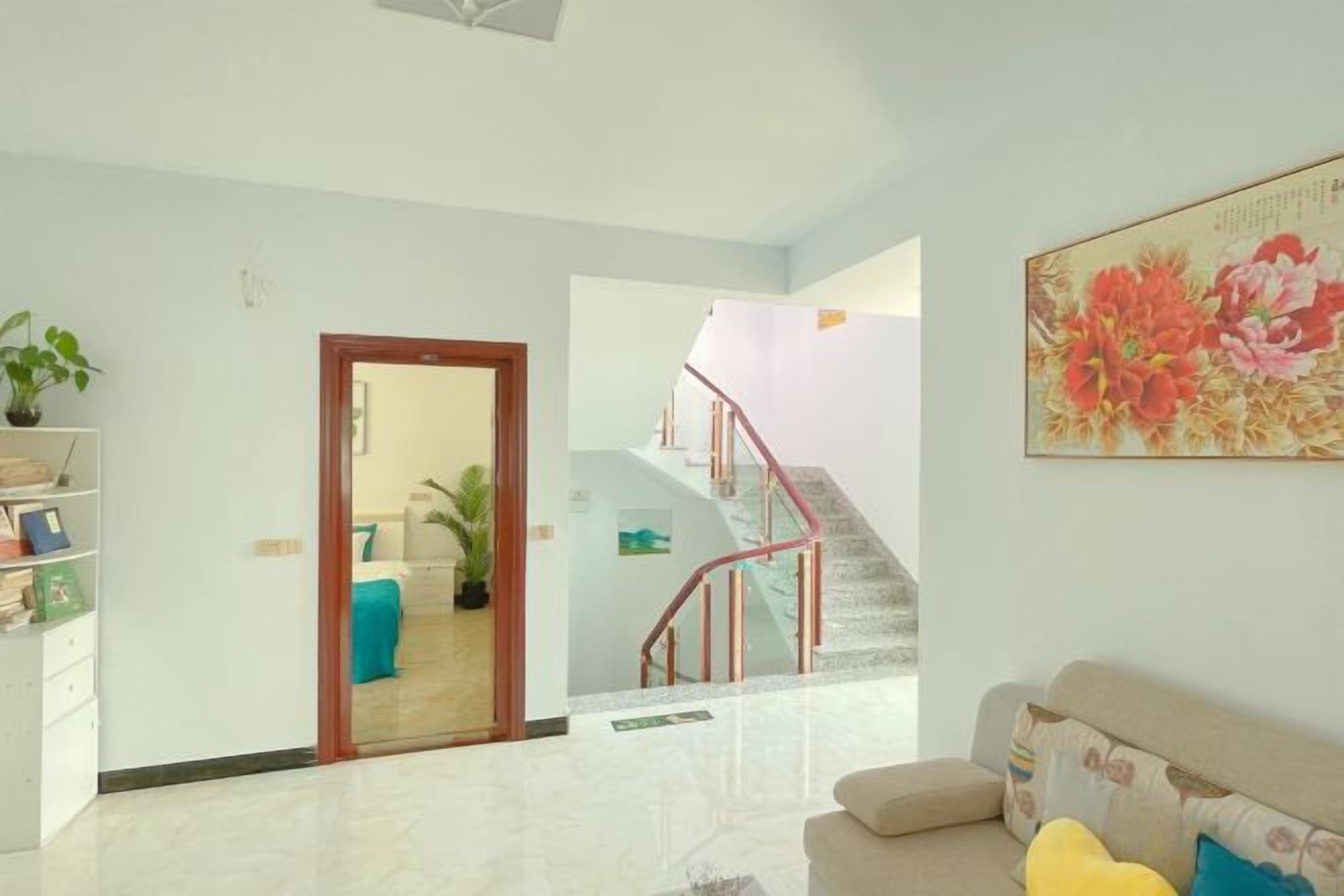 A living room with a sofa, a staircase, and a door leading to another room.