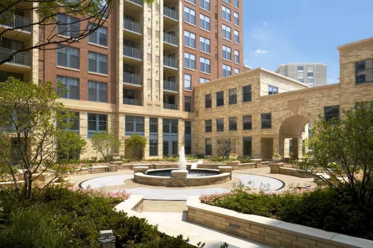 A courtyard with a central fountain, surrounded by brick buildings with multiple floors and balconies.