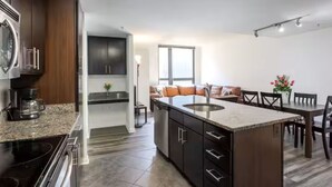 A modern kitchen with dark wood cabinets, a granite countertop, and a built-in oven. - Pentagon Luxe Apartments (Arlington)