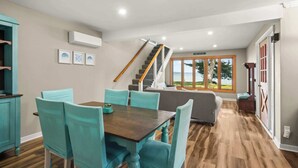 A dining area with teal chairs and a wooden table, a staircase, and a view of the outdoors. - Torch Ever Blue | SandBar | Waterfront (Rapid City)