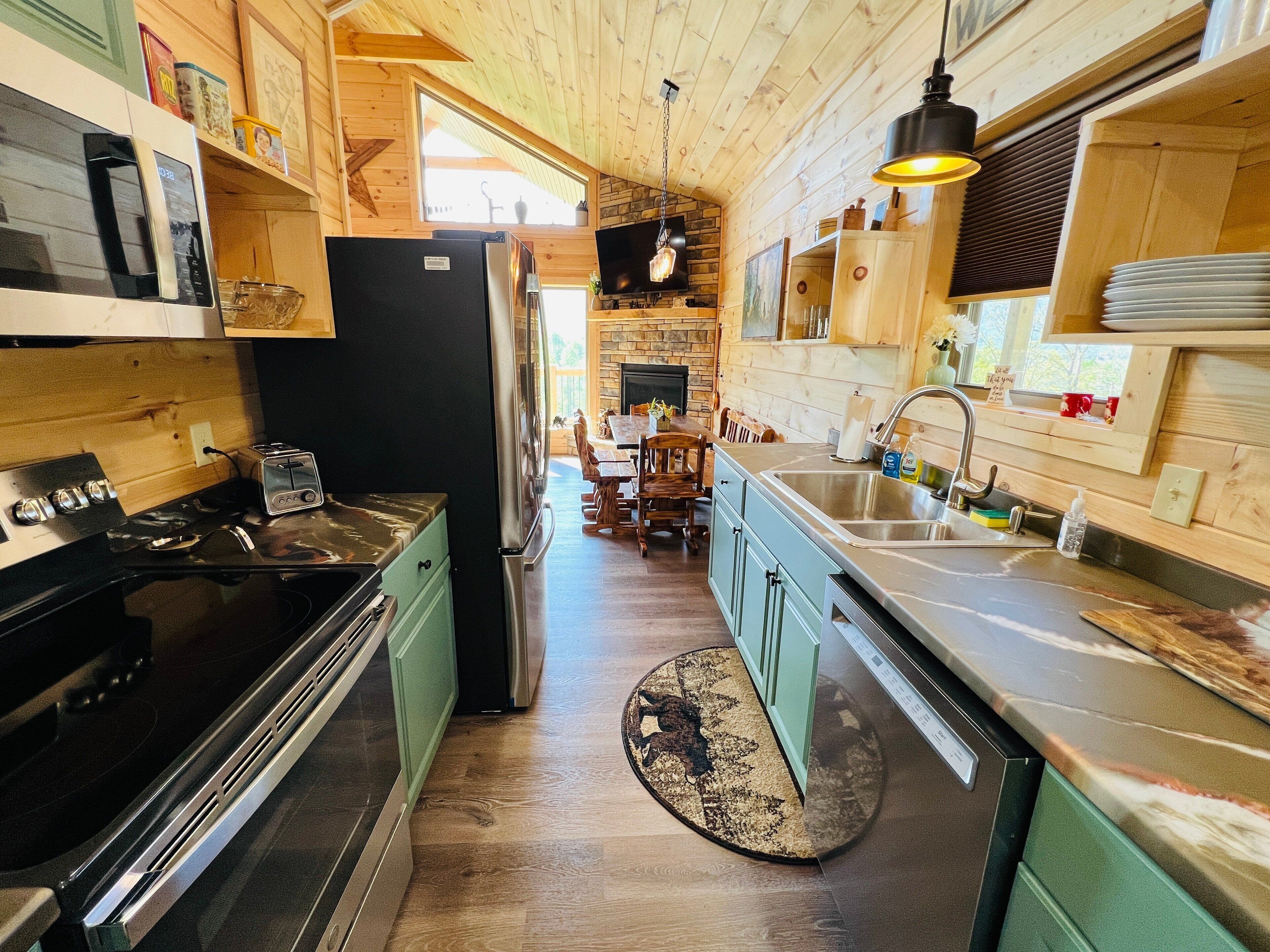 Een functionele keuken met een fornuis, gootsteen en koelkast. Er is een eethoek met een tafel en stoelen.