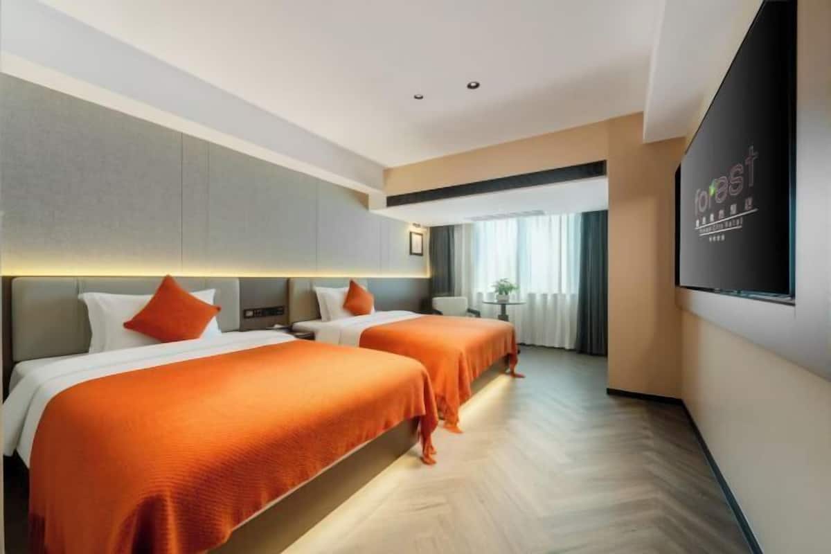 Habitación de hotel con dos camas, televisión, escritorio y ventana con cortinas.