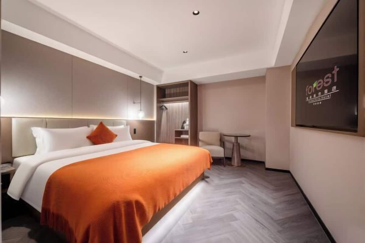 Una habitación de hotel moderna con una cama grande, una mesita pequeña y un área de descanso.