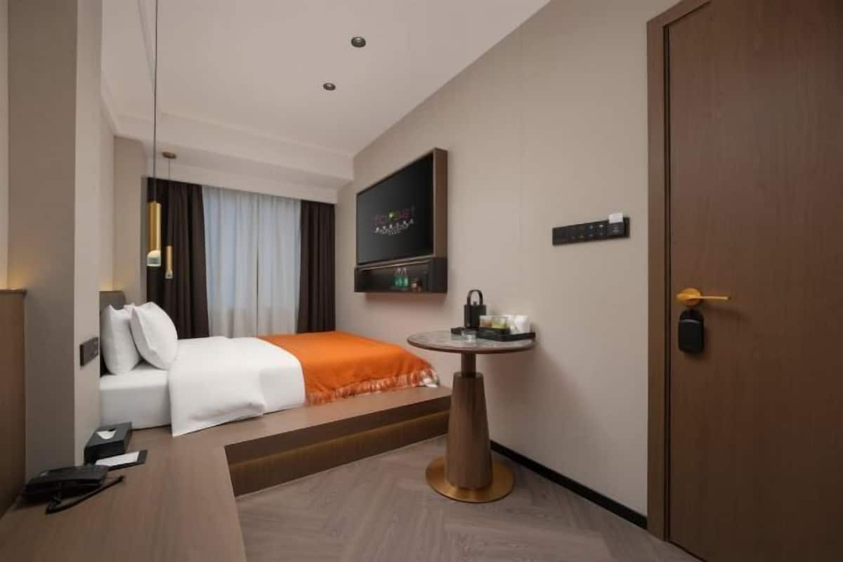 Una habitación de hotel con una cama, un escritorio, un televisor y una puerta.