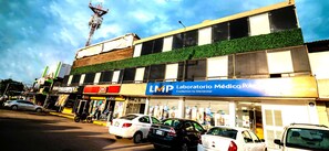 Stylish commercial building with a pharmacy and adjacent businesses, featuring a lush green garden on the upper level.