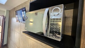 A wall-mounted microwave with a digital display and multiple cooking settings.