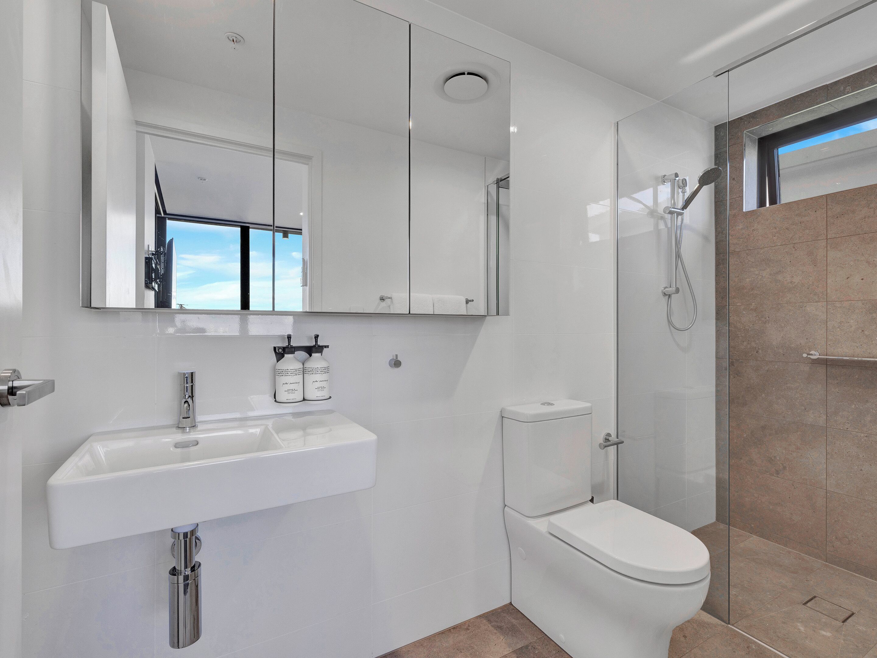 A modern bathroom with a white sink, toilet, and shower.