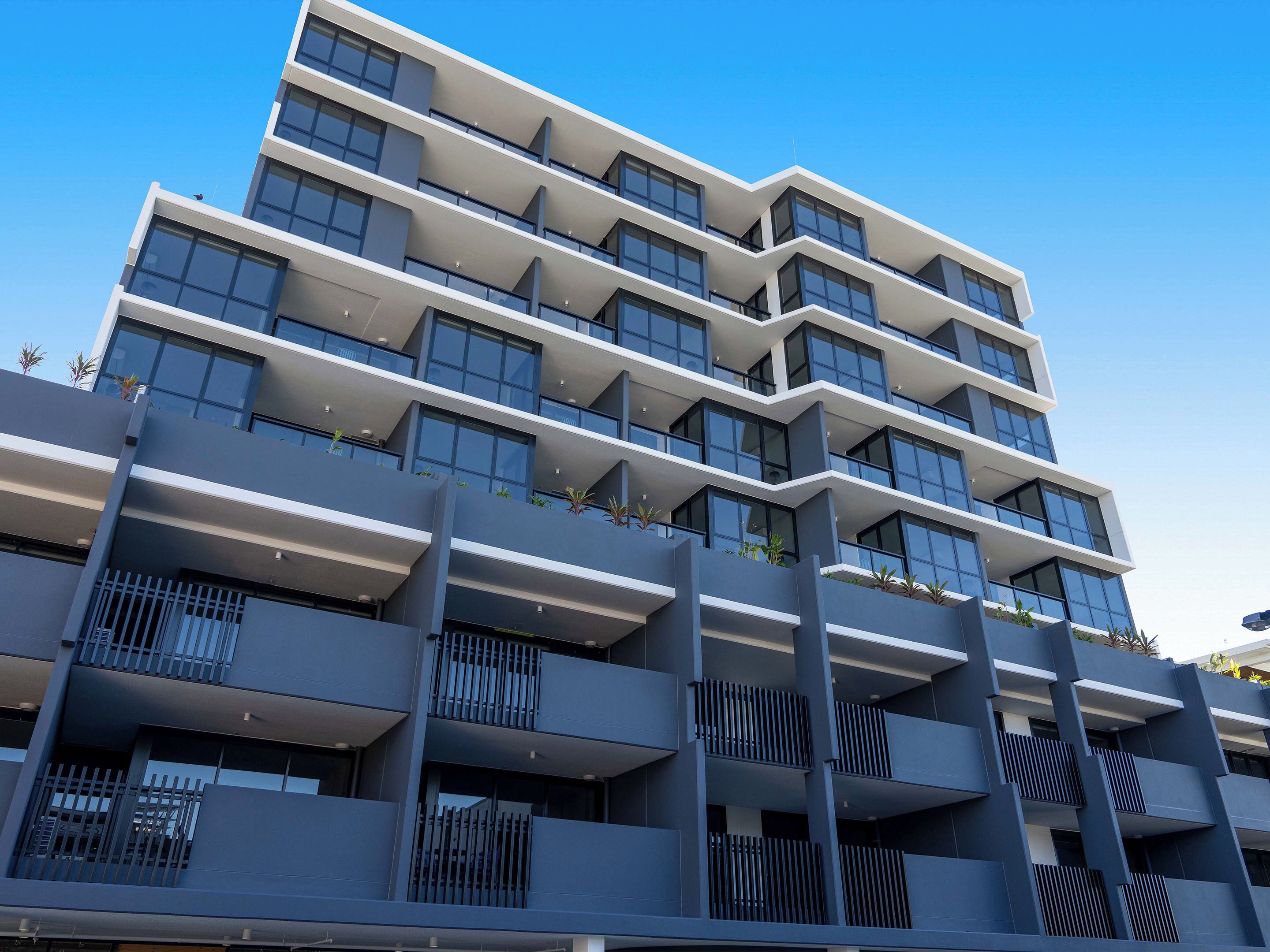 A multi-story building with balconies and large windows.