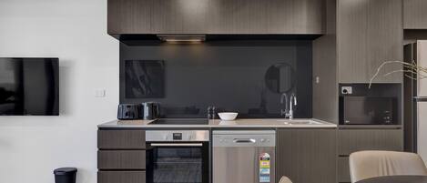A modern kitchen with dark wood cabinets, a built-in oven, a dishwasher, a microwave, and a large window above the sink.